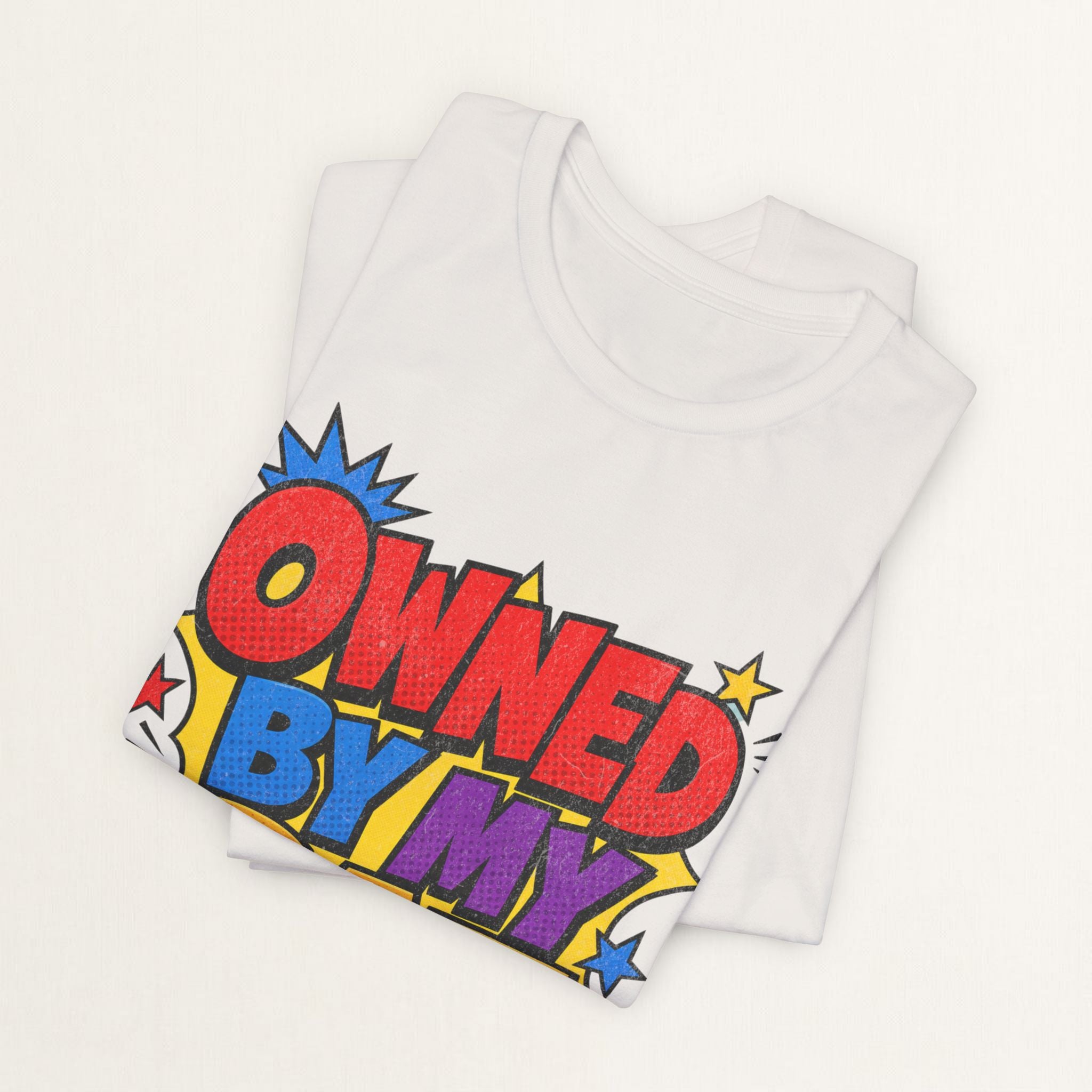 Folded vintage white Owned By My Cat t-shirt with colorful comic-style graphic