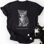 Black garment-dyed cotton tee featuring grumpy cat graphic and humorous 'Not Taking Questions' slogan