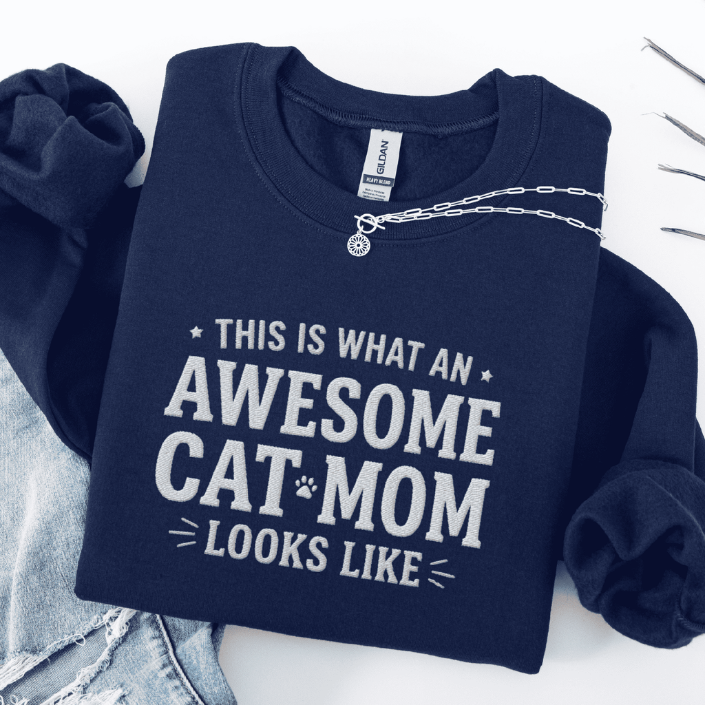 Navy awesome cat mom embroidered sweatshirt with “This Is What An Awesome Cat Mom Looks Like” text, folded flat on light denim