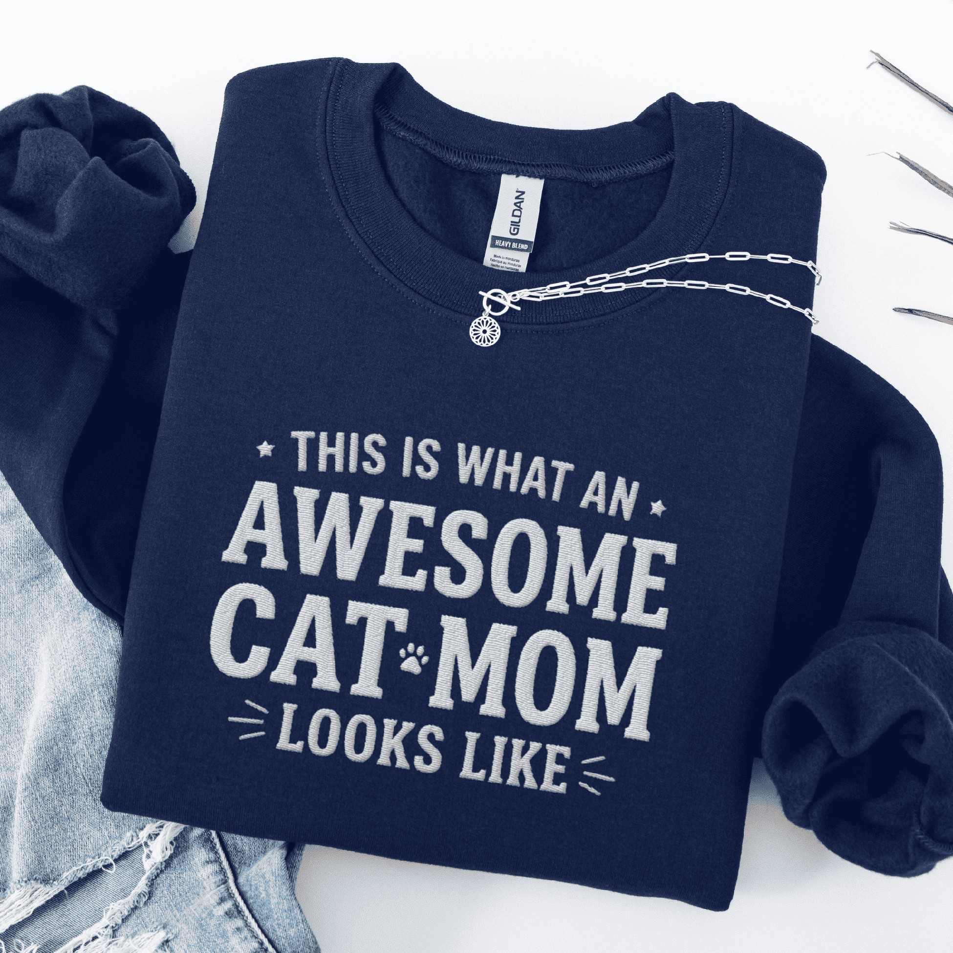 Navy awesome cat mom embroidered sweatshirt with “This Is What An Awesome Cat Mom Looks Like” text, folded flat on light denim