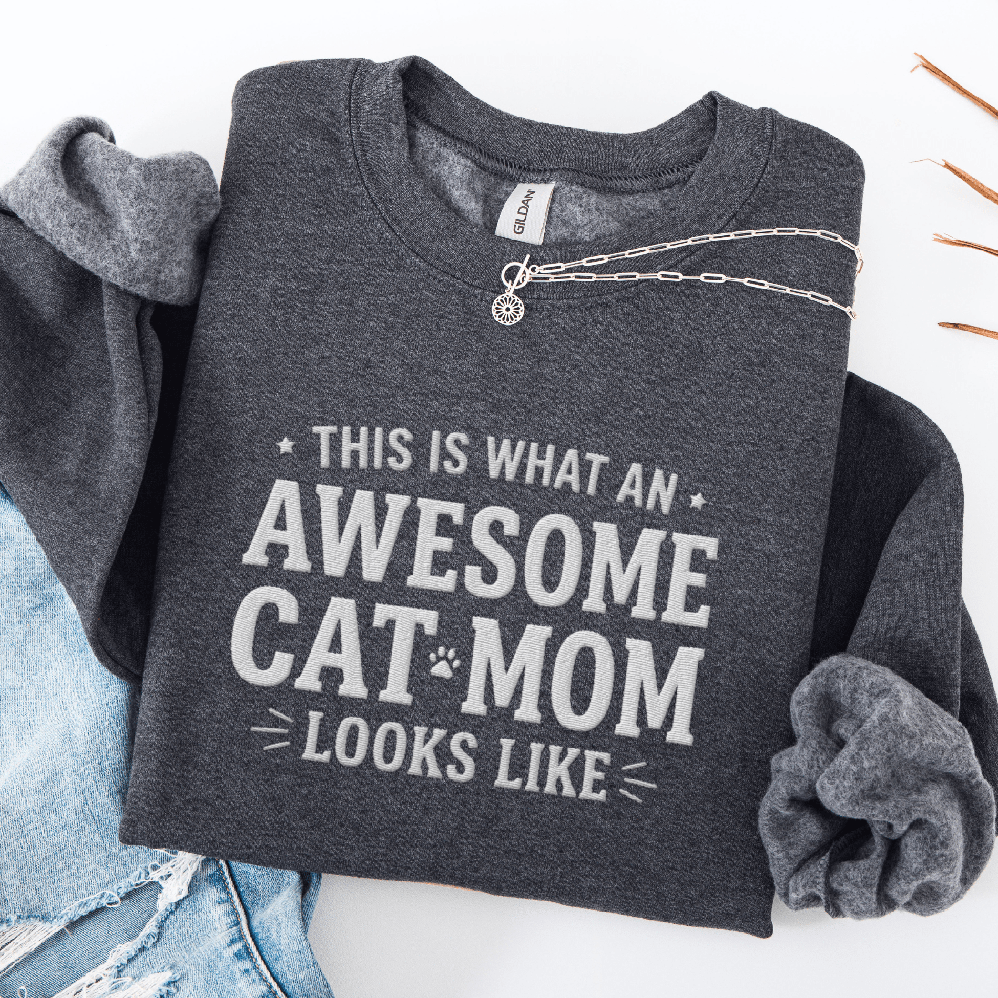 Dark Heather awesome cat mom embroidered sweatshirt with “This Is What An Awesome Cat Mom Looks Like” text, folded flat on light denim