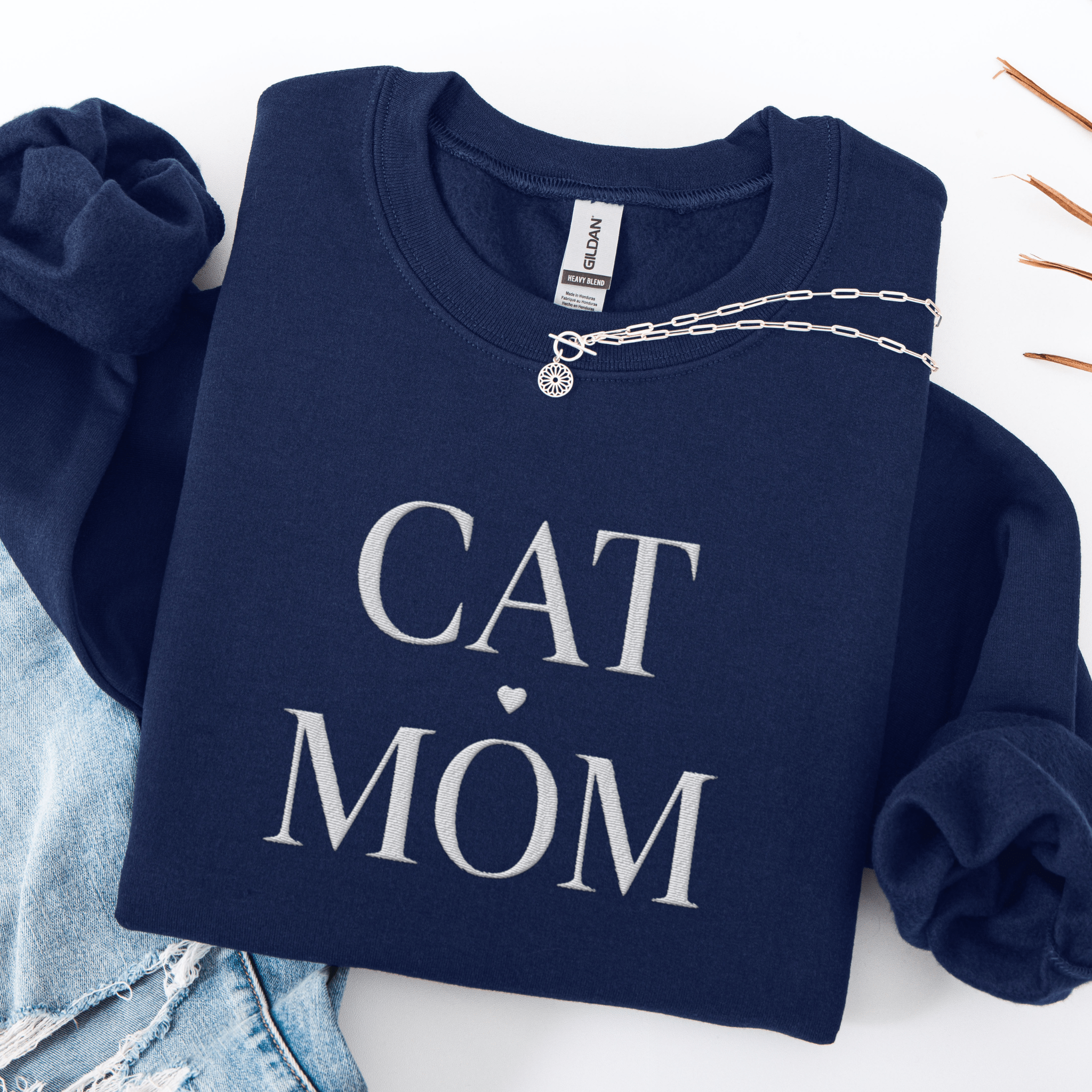 Navy cat mom embroidered sweatshirt, folded flat on light denim