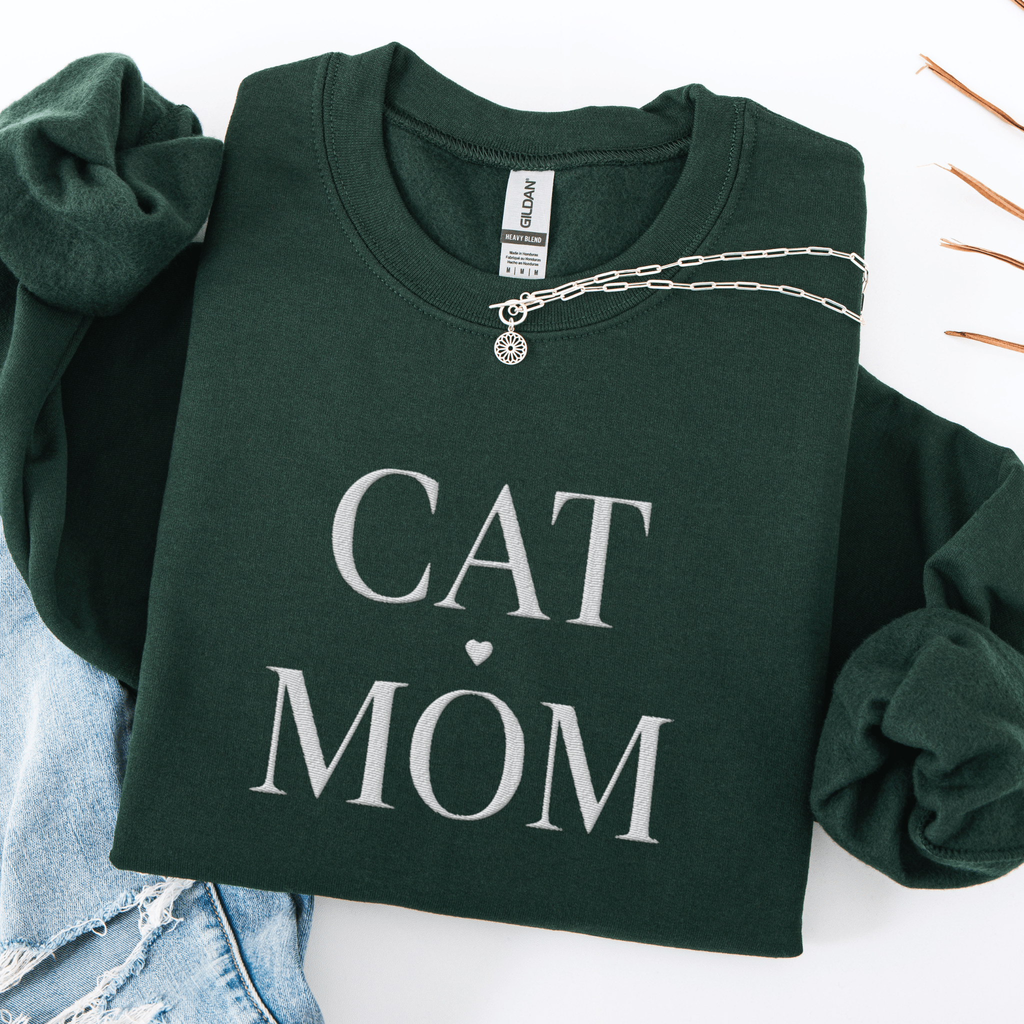 Forest Green cat mom embroidered sweatshirt, folded flat on light denim