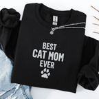 Black best cat mom ever embroidered sweatshirt with paw print detail, folded flat on light denim