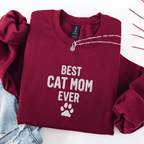 Maroon best cat mom ever embroidered sweatshirt with paw print detail, folded flat on light denim