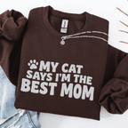 Dark Chocolate cat mom embroidered sweatshirt with “My Cat Says I’m The Best Mom” text, folded flat on light denim