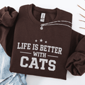 Dark Chocolate cat embroidered sweatshirt with “Life Is Better With Cats” text, folded flat on light denim