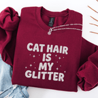 Maroon cat embroidered sweatshirt with “Cat Hair Is My Glitter” text, folded flat on light denim