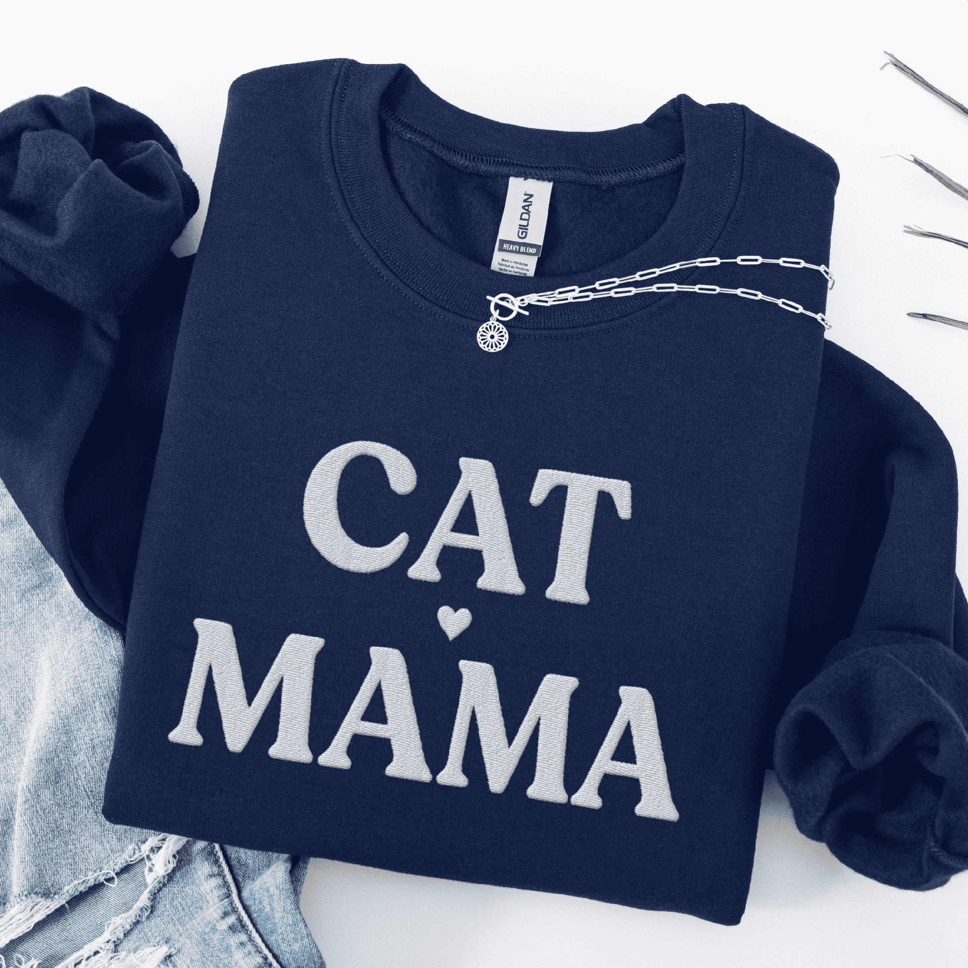 Navy cat mama embroidered sweatshirt, folded flat on light denim