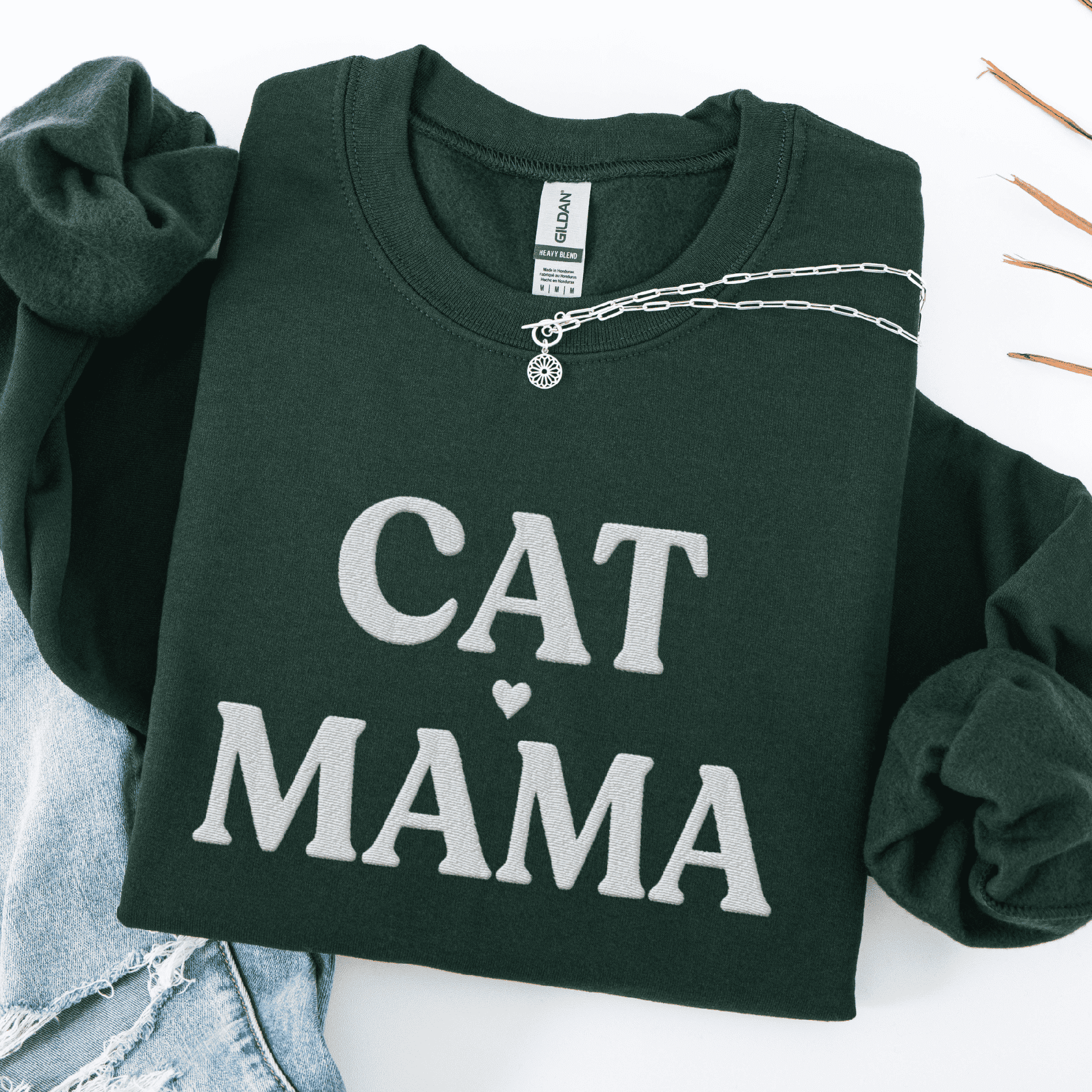 Forest Green cat mama embroidered sweatshirt, folded flat on light denim
