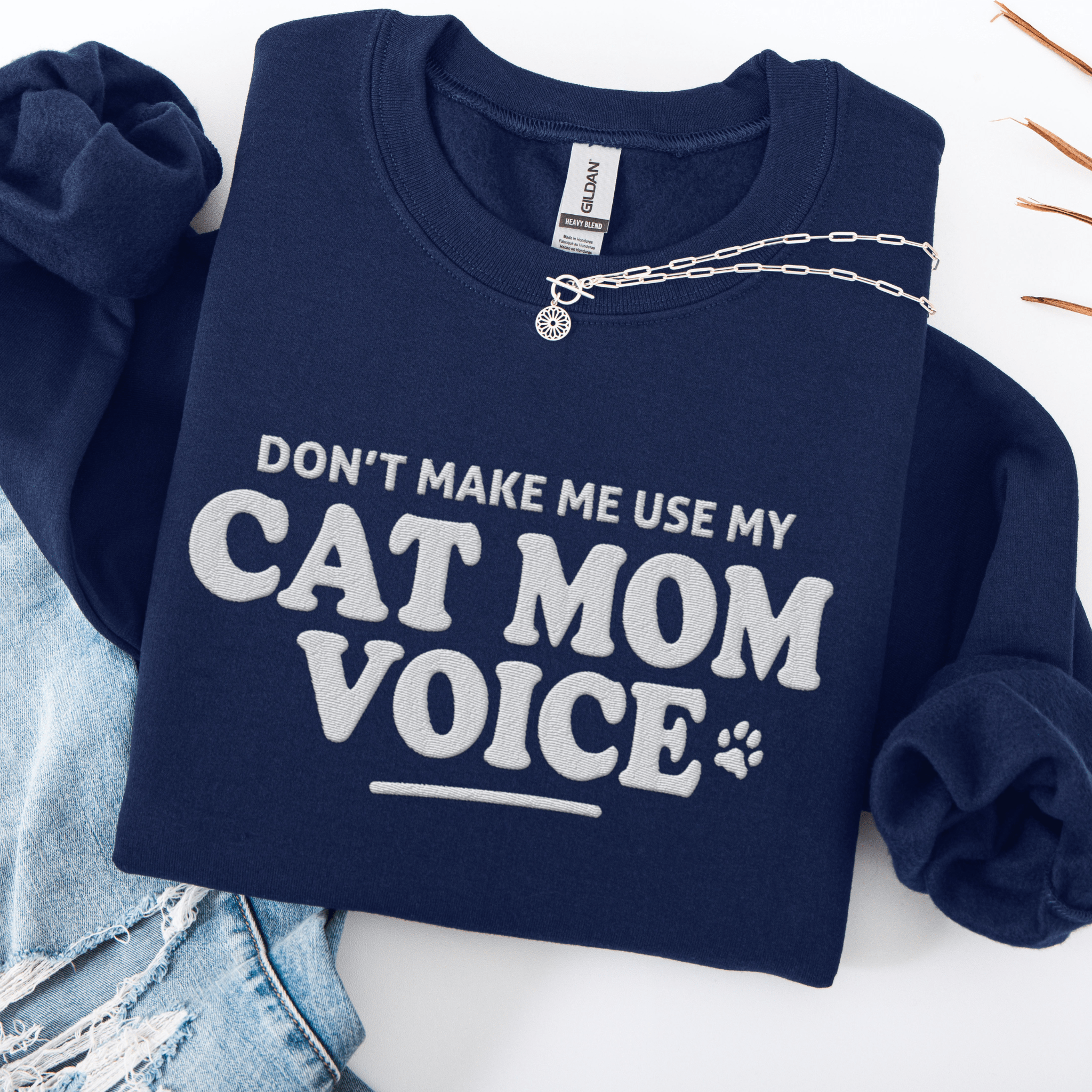 Navy cat mom embroidered sweatshirt with “Don’t Make Me Use My Cat Mom Voice” text, folded flat on light denim