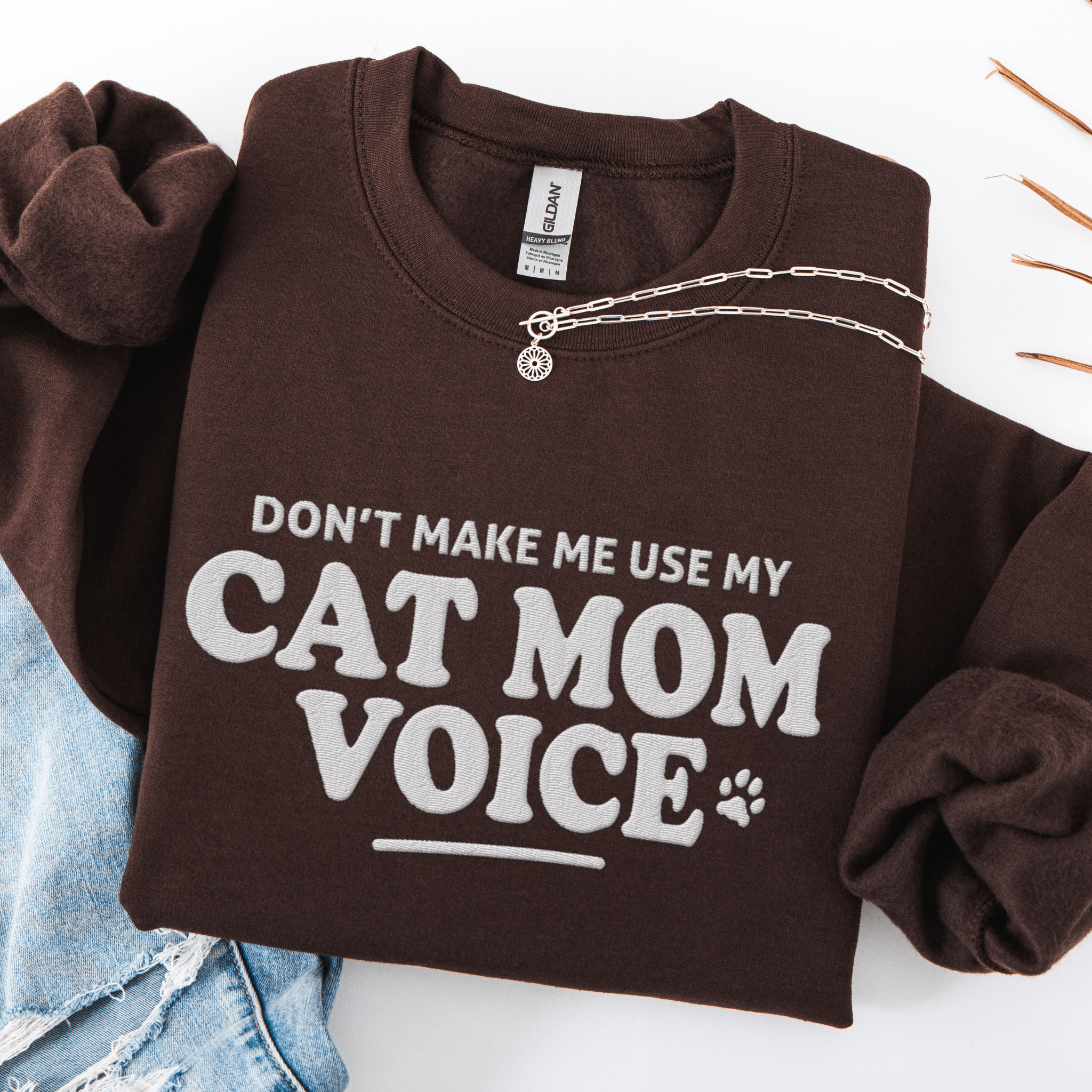 Dark Chocolate cat mom embroidered sweatshirt with “Don’t Make Me Use My Cat Mom Voice” text, folded flat on light denim