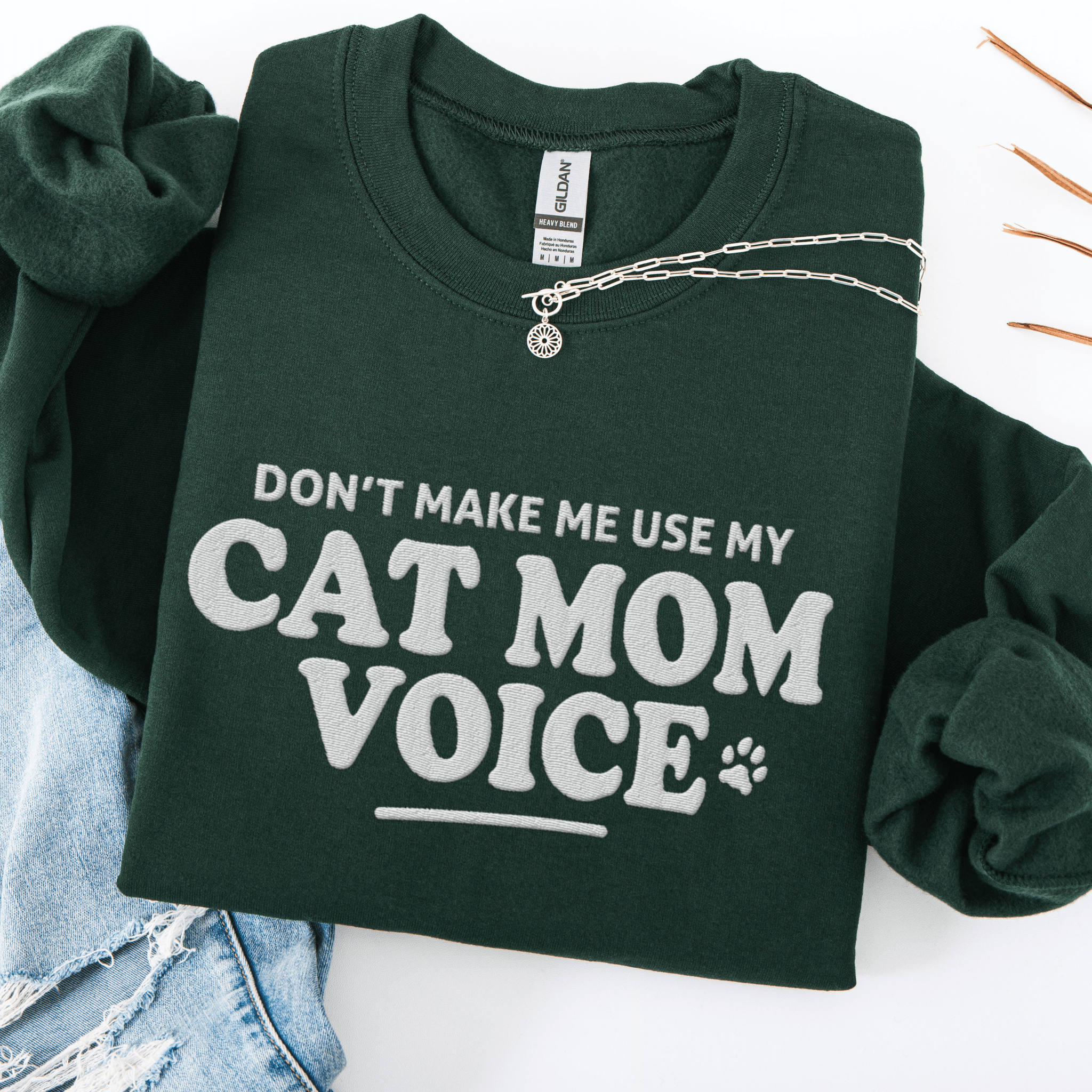 Forest Green cat mom embroidered sweatshirt with “Don’t Make Me Use My Cat Mom Voice” text, folded flat on light denim