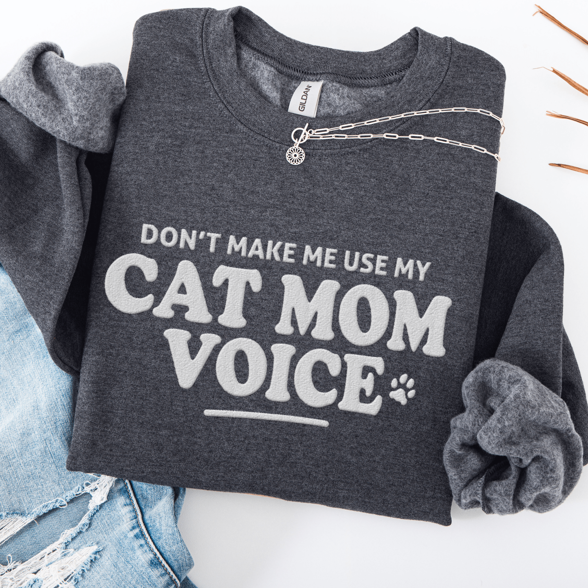 Dark Heather cat mom embroidered sweatshirt with “Don’t Make Me Use My Cat Mom Voice” text, folded flat on light denim