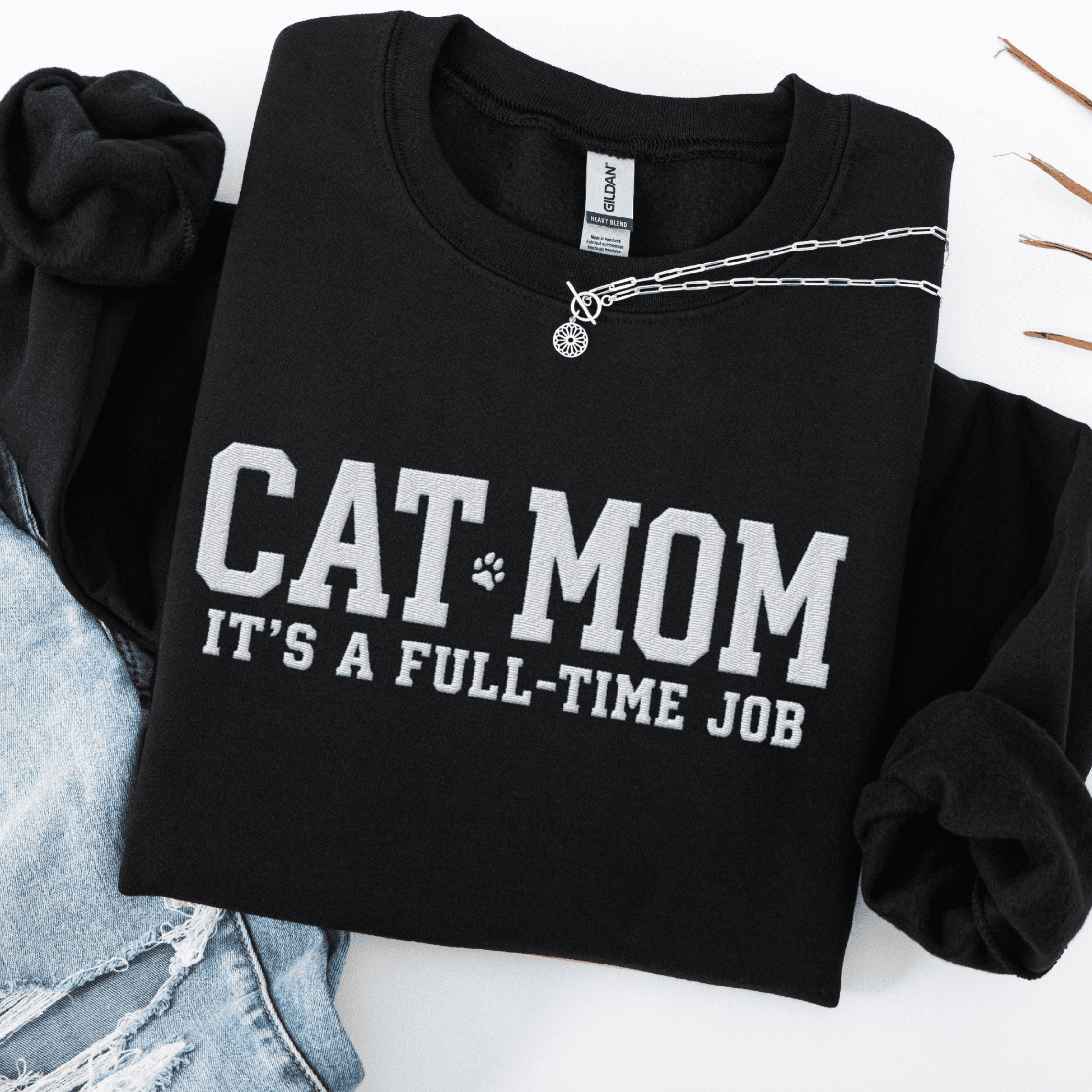 Black cat mom embroidered sweatshirt with “Cat Mom It’s A Full-Time Job” text, folded flat on light denim