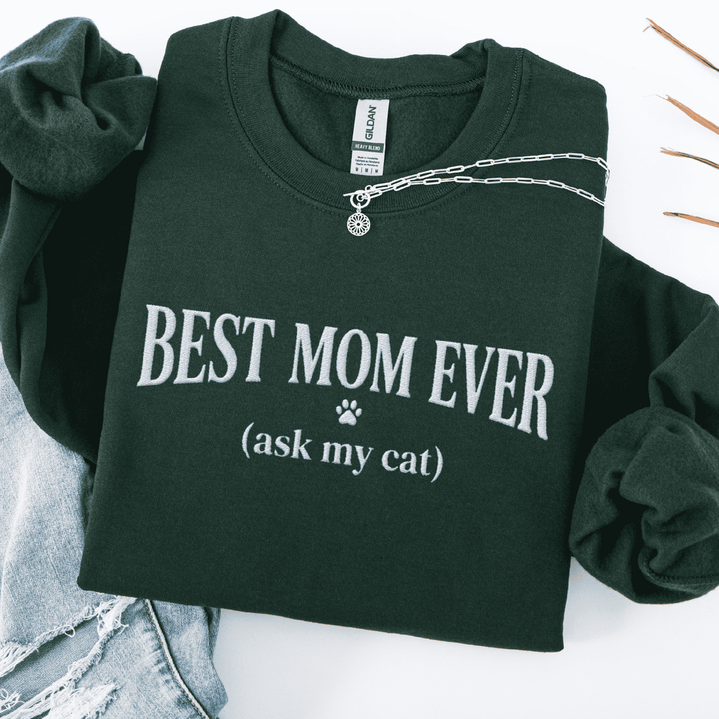 Forest Green cat mom embroidered sweatshirt with “Best Mom Ever (ask my cat)” text, folded flat on light denim