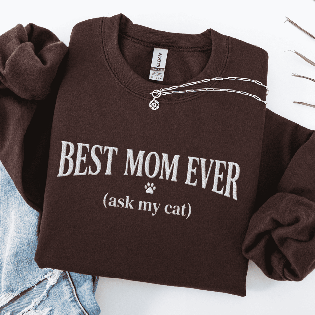 Dark Chocolate cat mom embroidered sweatshirt with “Best Mom Ever (ask my cat)” text, folded flat on light denim