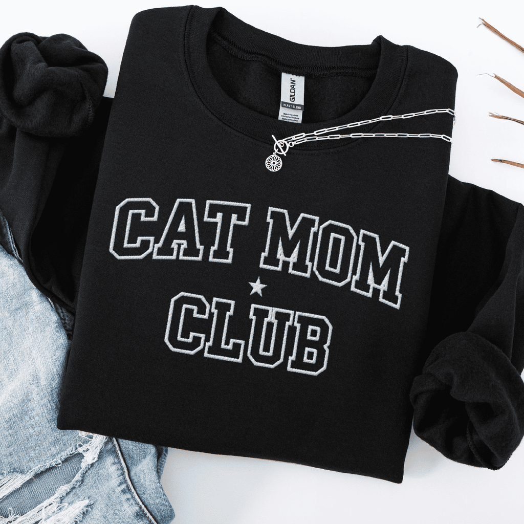 Black cat mom club embroidered sweatshirt, folded flat on light denim