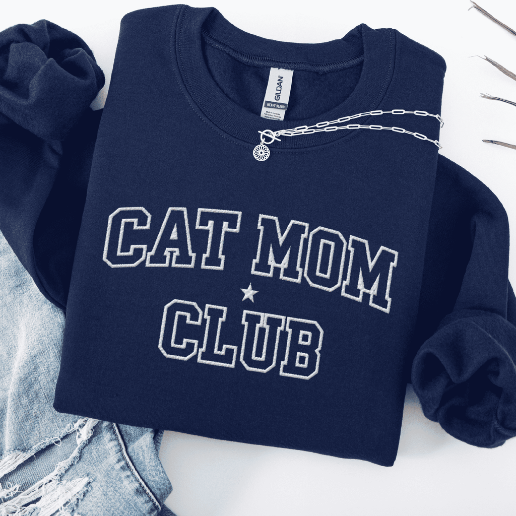 Navy cat mom club embroidered sweatshirt, folded flat on light denim