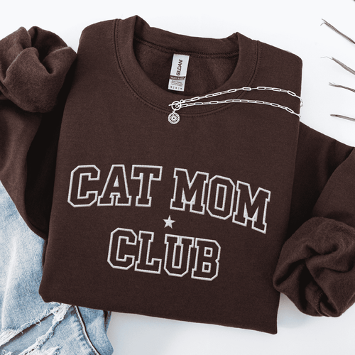 Dark Chocolate cat mom club embroidered sweatshirt, folded flat on light denim