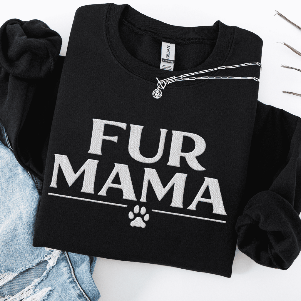 Black fur mama embroidered sweatshirt with paw print detail, folded flat on light denim