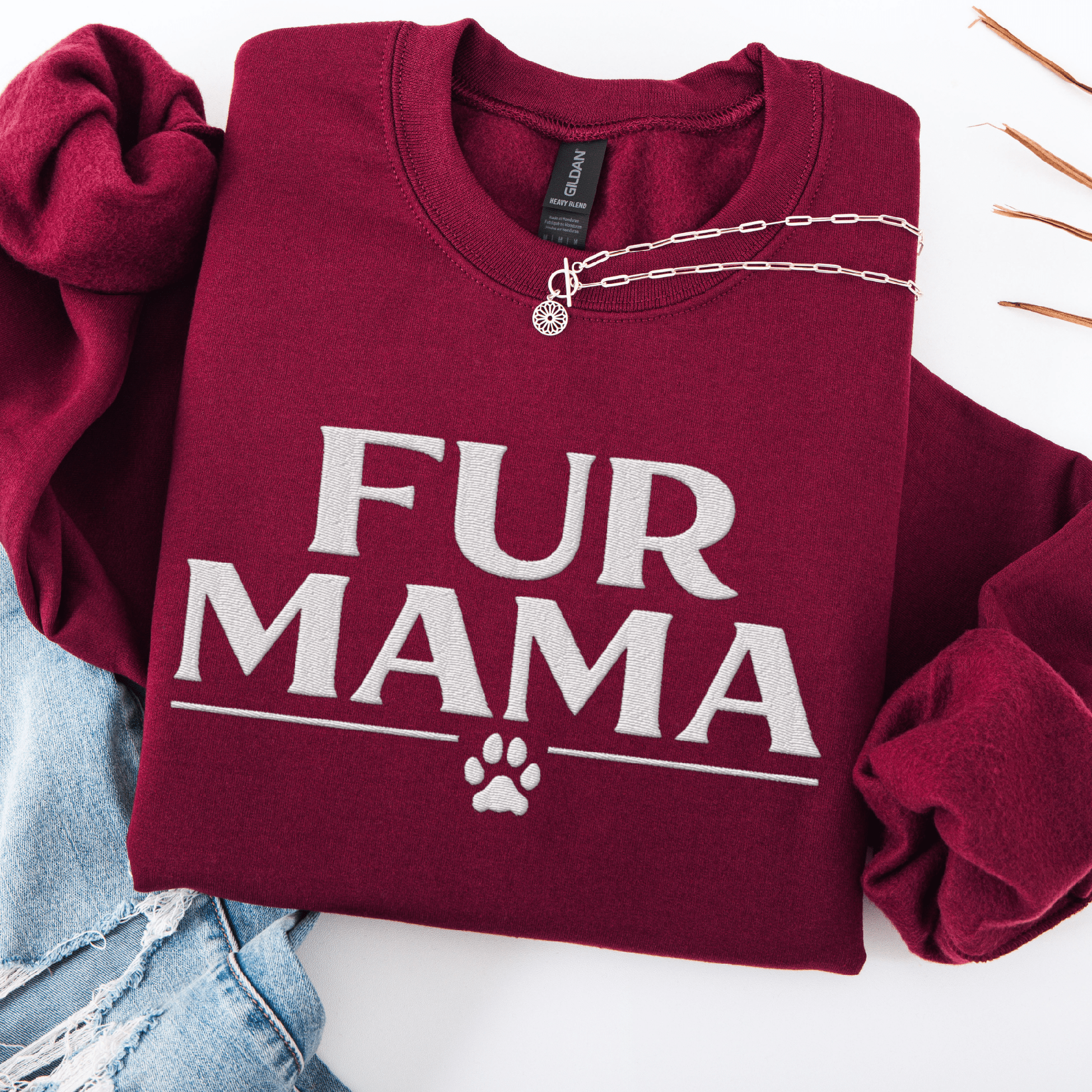 Maroon fur mama embroidered sweatshirt with paw print detail, folded flat on light denim