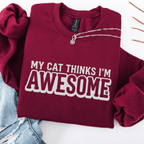 Maroon cat embroidered sweatshirt with “My Cat Thinks I’m Awesome” text, folded flat on light denim