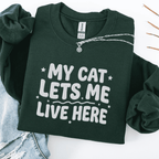 Forest Green cat embroidered sweatshirt with “My Cat Lets Me Live Here” text, folded flat on light denim