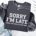Dark Heather cat embroidered sweatshirt with “Sorry I’m Late” text, folded flat on light denim