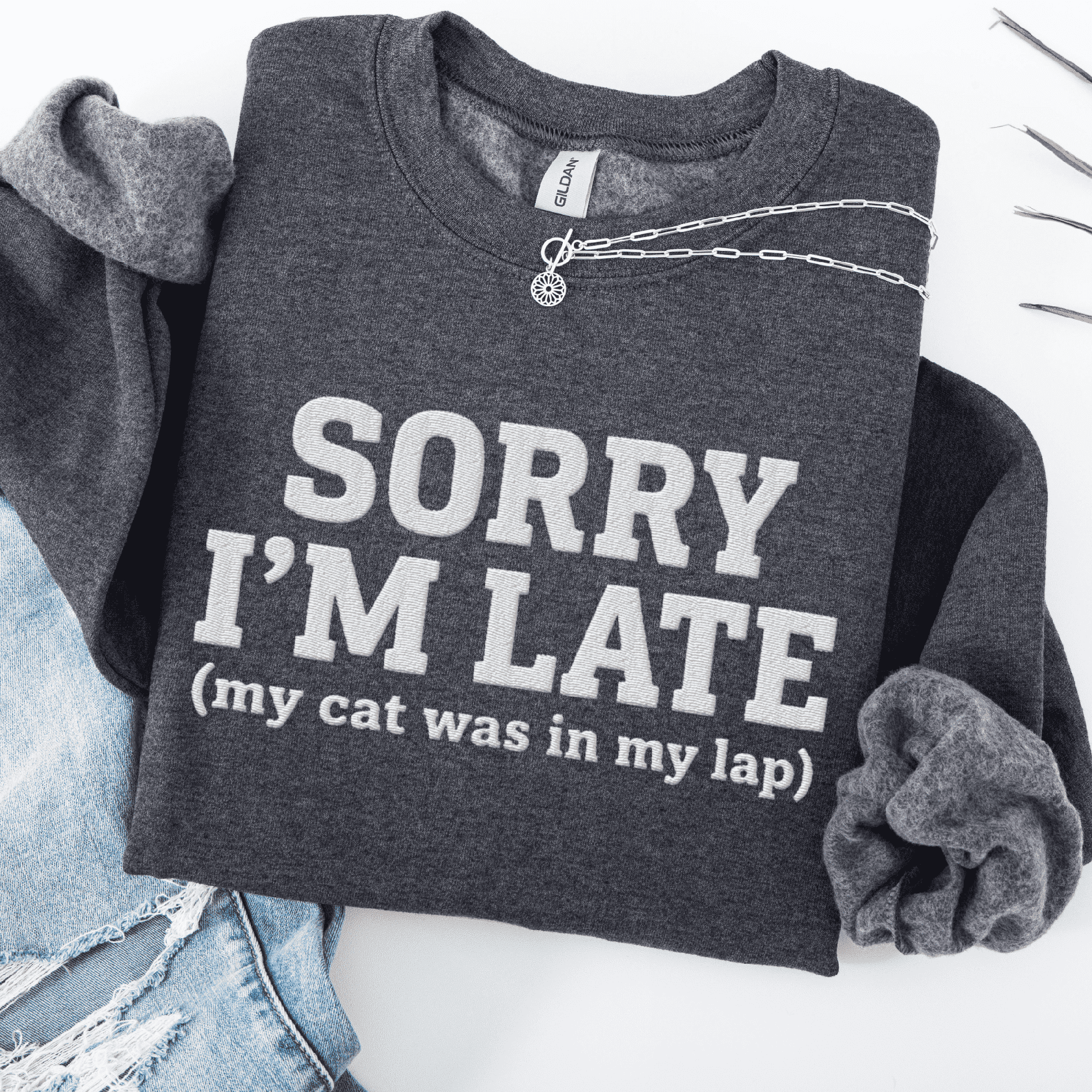 Dark Heather cat embroidered sweatshirt with “Sorry I’m Late” text, folded flat on light denim