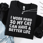 Black cat embroidered sweatshirt with “I Work Hard So My Cat Can Have A Better Life” text, folded flat on light denim