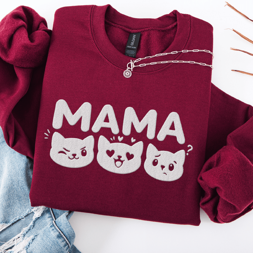 Maroon mama embroidered sweatshirt with cat face design, folded flat on light denim
