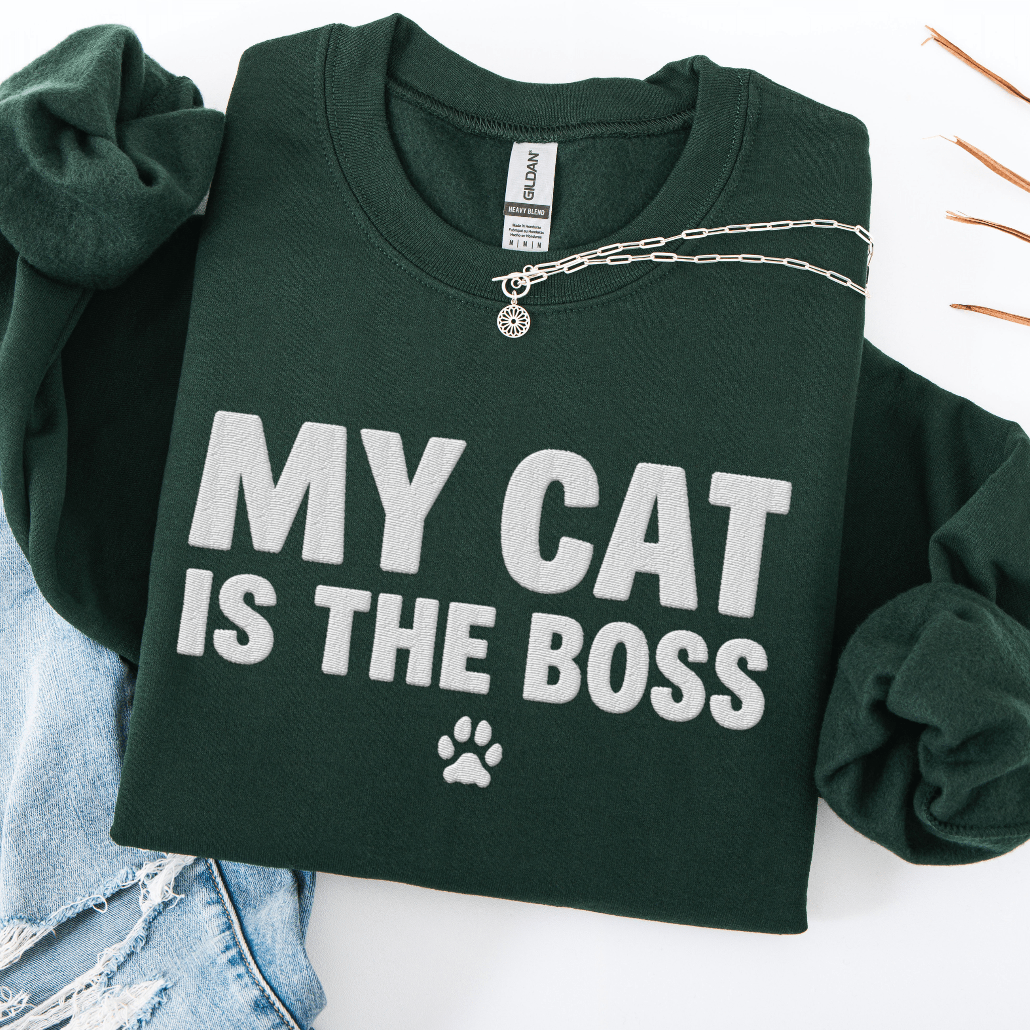 Forest Green cat embroidered sweatshirt with “My Cat Is The Boss” text, folded flat on light denim