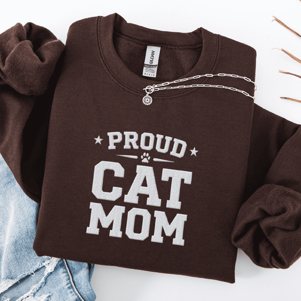 Dark Chocolate proud cat mom embroidered sweatshirt with “Proud Cat Mom” text, folded flat on light denim