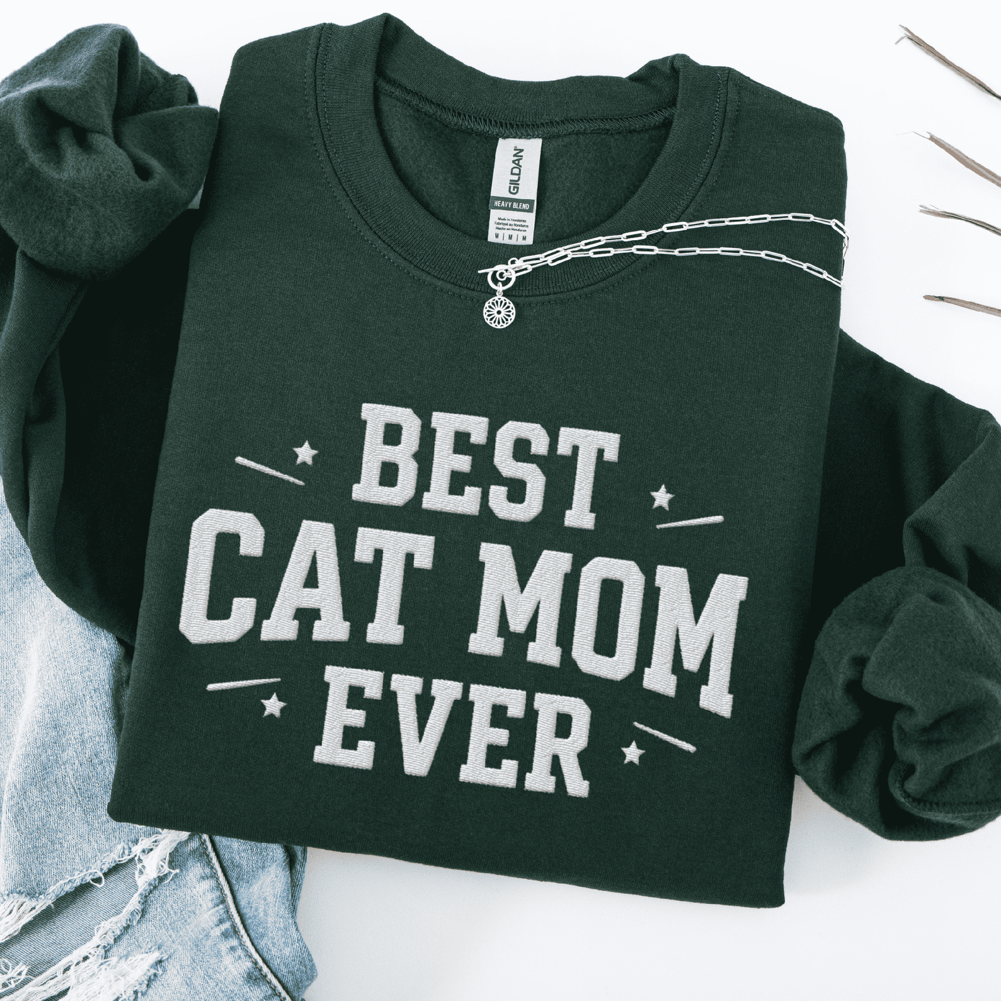 Forest green cat mom embroidered sweatshirt with “Best Cat Mom Ever” text, styled flat on light denim