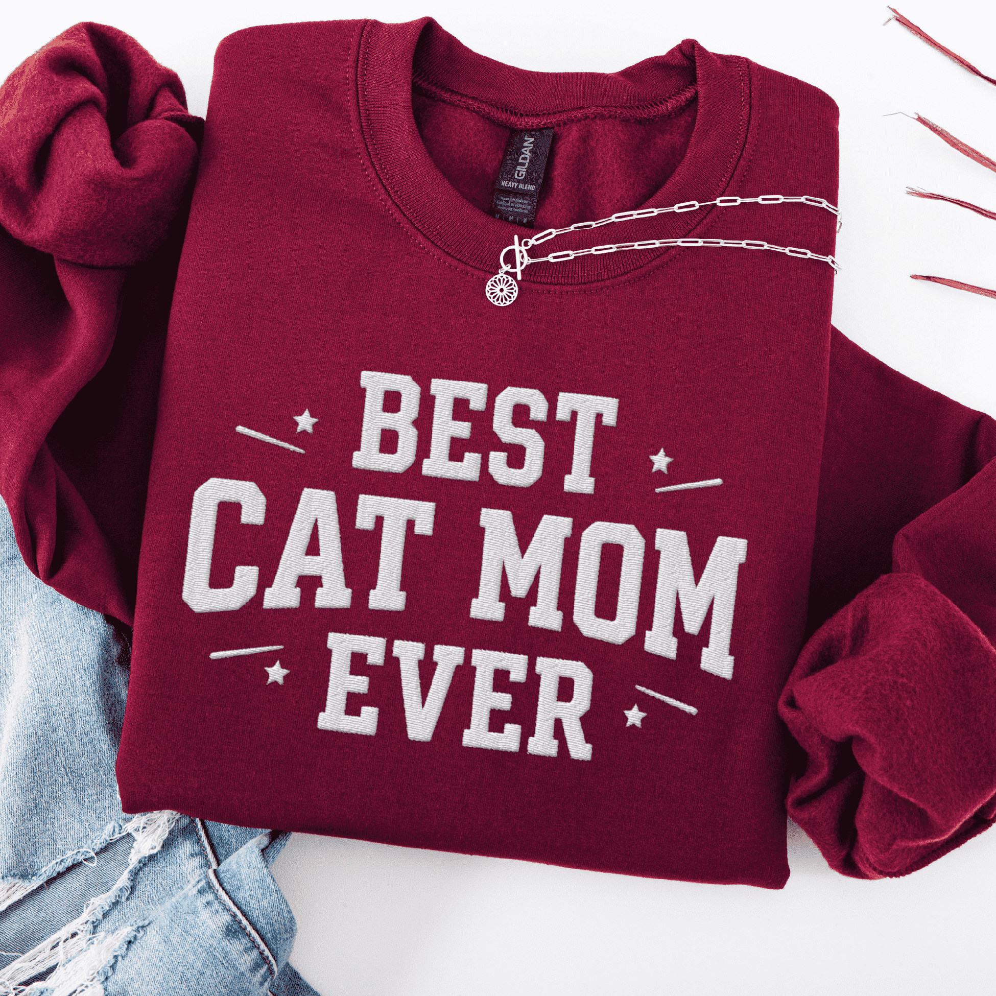 Maroon cat mom embroidered sweatshirt with “Best Cat Mom Ever” text, styled flat on light denim