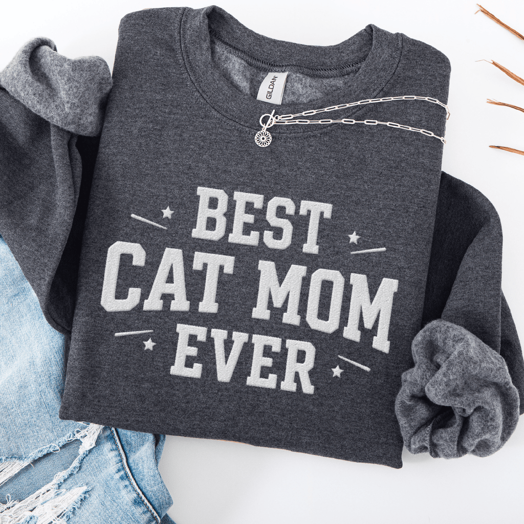 Dark heather cat mom embroidered sweatshirt with “Best Cat Mom Ever” text, styled flat on light denim