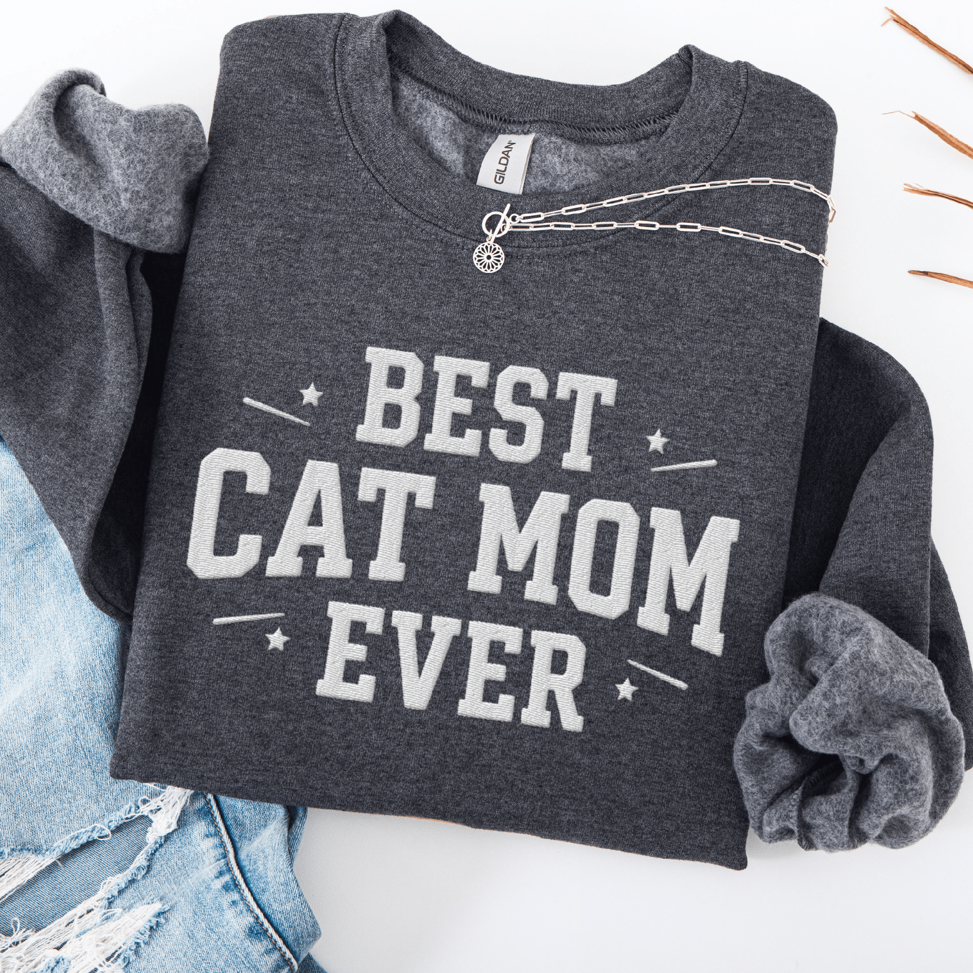 Dark heather cat mom embroidered sweatshirt with “Best Cat Mom Ever” text, styled flat on light denim