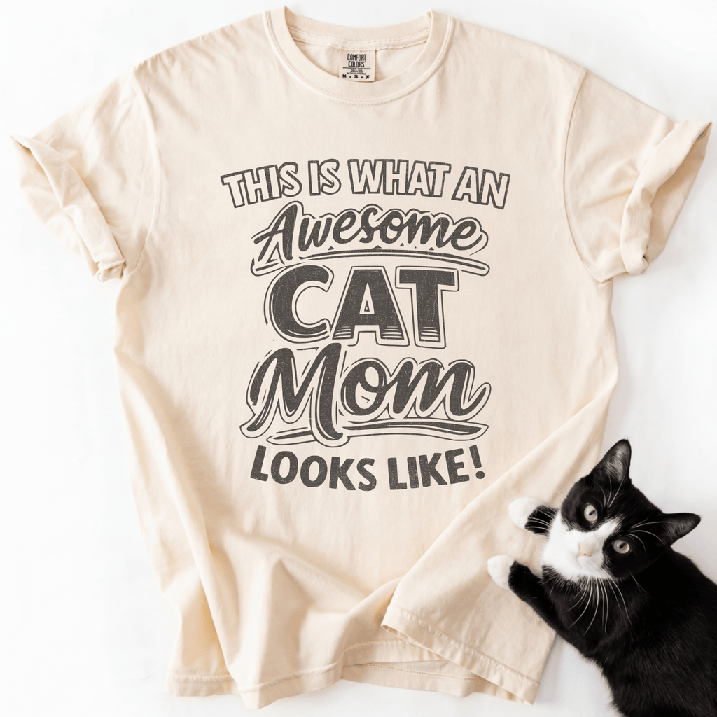 Ivory cat mom t-shirt with “This Is What an Awesome Cat Mom Looks Like” graphic displayed in a flat lay with a black cat