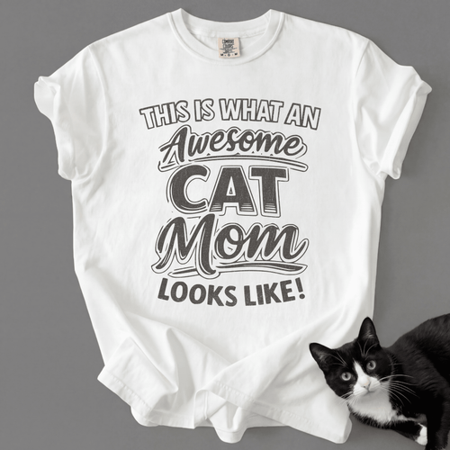 White cat mom t-shirt with “This Is What an Awesome Cat Mom Looks Like” graphic shown with a black cat at the bottom corner