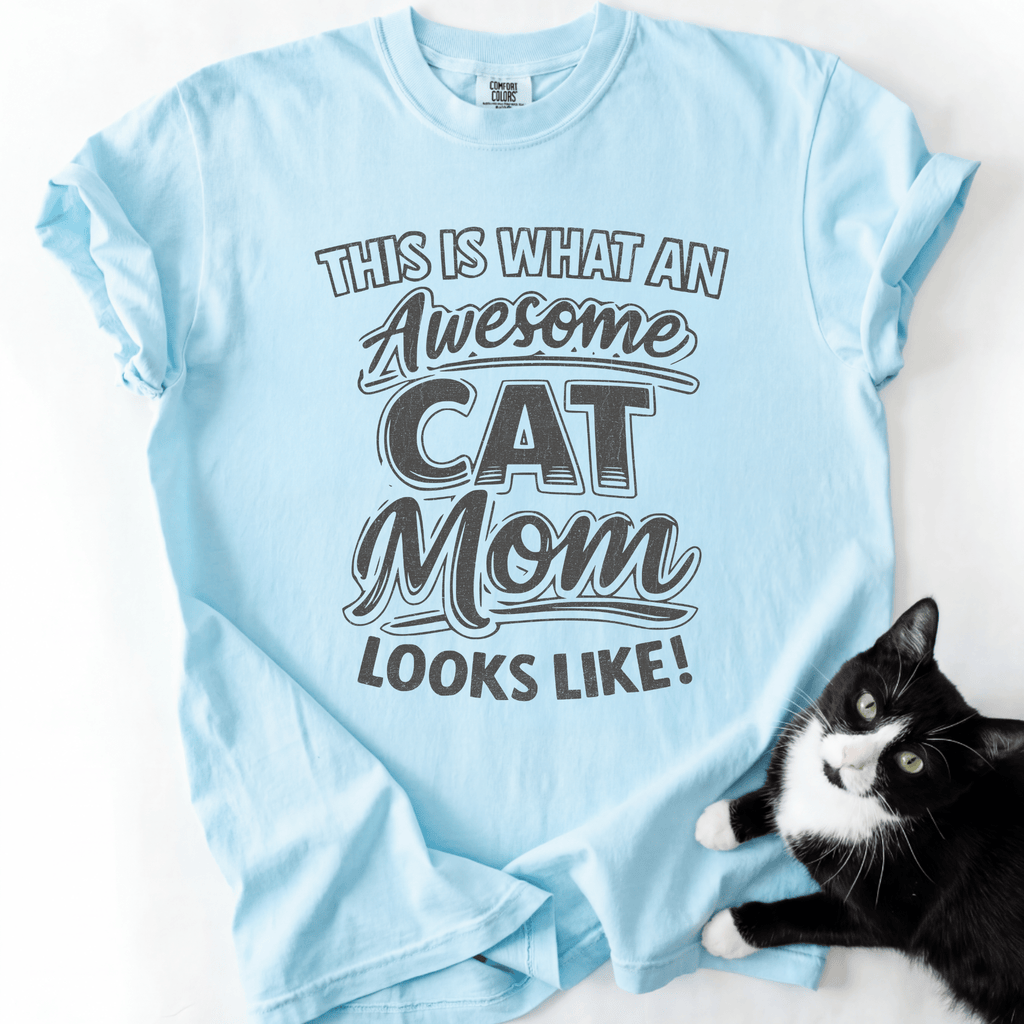 Chambray cat mom t-shirt with “This Is What an Awesome Cat Mom Looks Like” graphic shown in a flat lay with a black cat