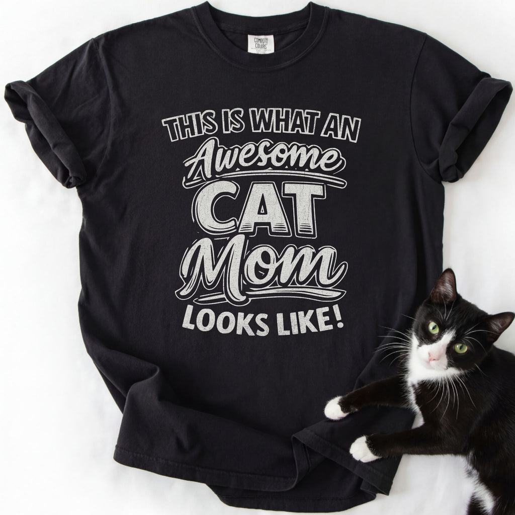 Black cat mom t shirt with “This Is What an Awesome Cat Mom Looks Like” design and black and white cat beside the shirt