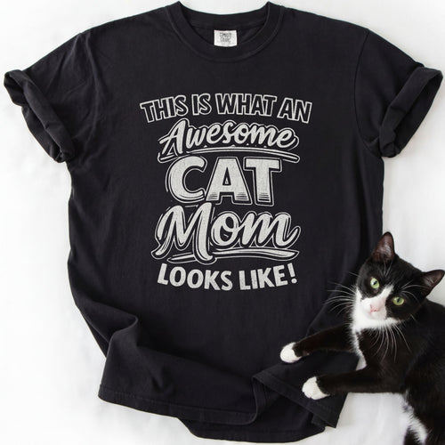 Black cat mom t shirt with “This Is What an Awesome Cat Mom Looks Like” design and black and white cat beside the shirt