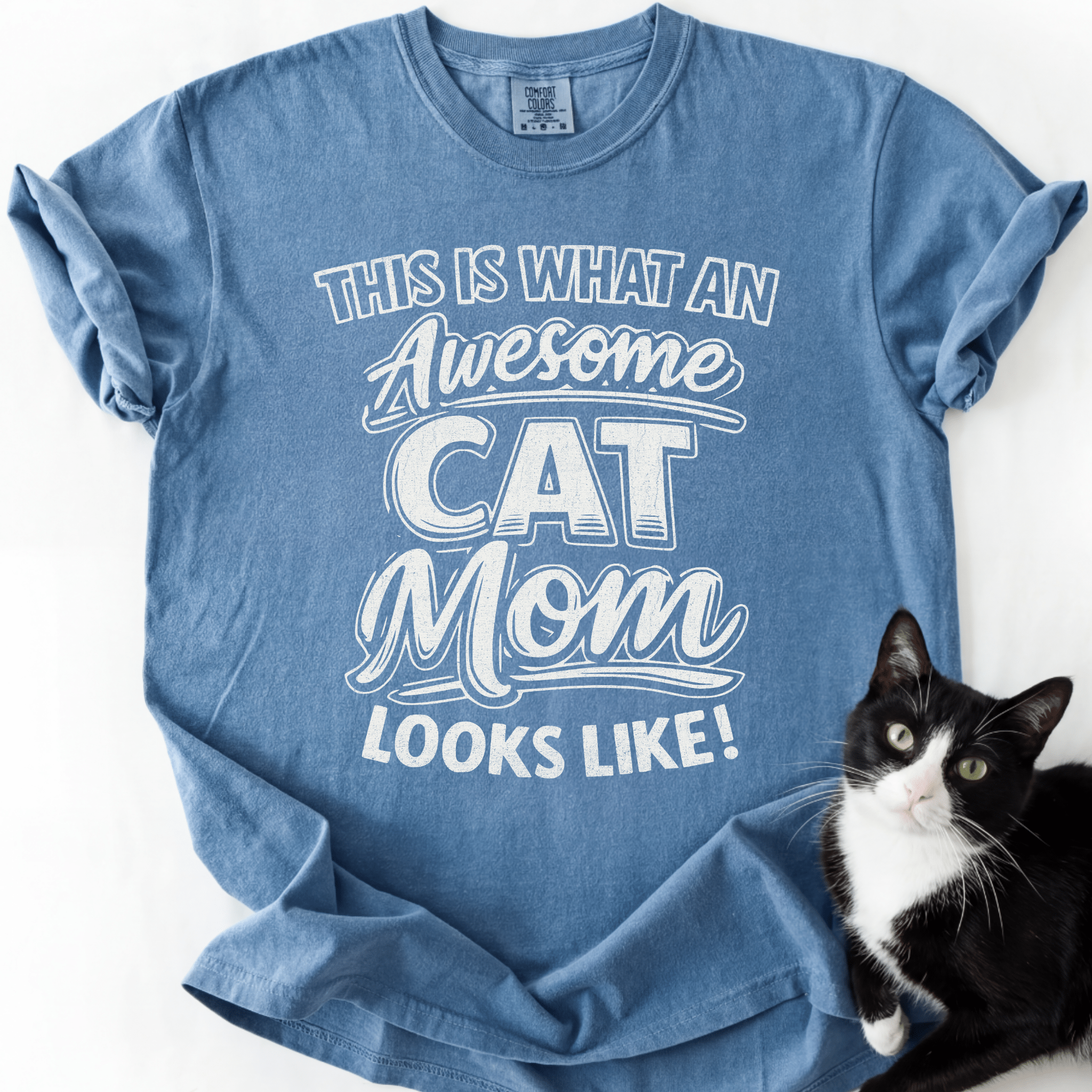 Blue Jean cat mom t shirt with “This Is What an Awesome Cat Mom Looks Like” design and black and white cat beside the shirt