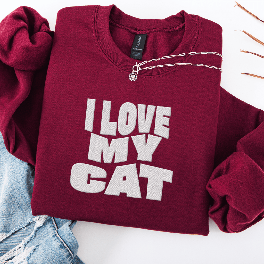 Maroon embroidered cat sweatshirt with the phrase “I Love My Cat” shown folded flat