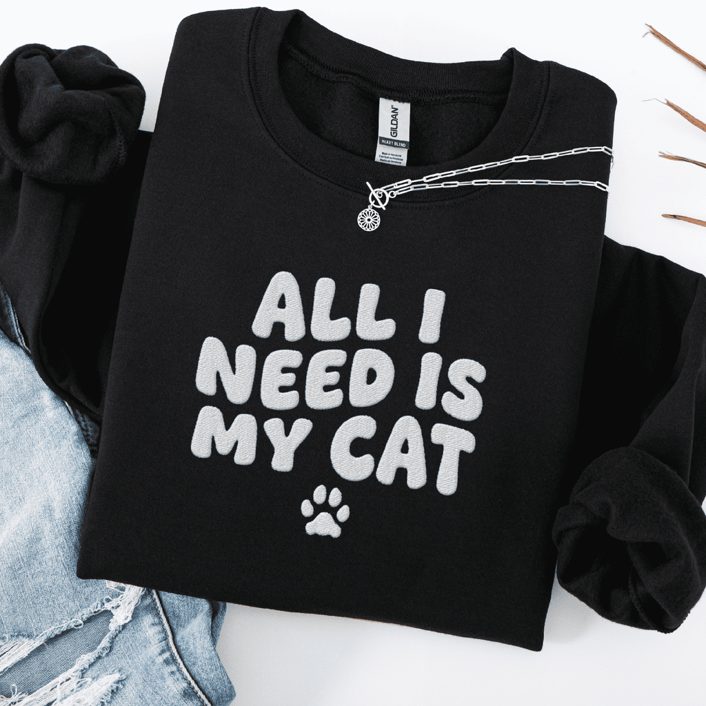 Black embroidered cat sweatshirt with the phrase “All I Need Is My Cat” shown folded flat