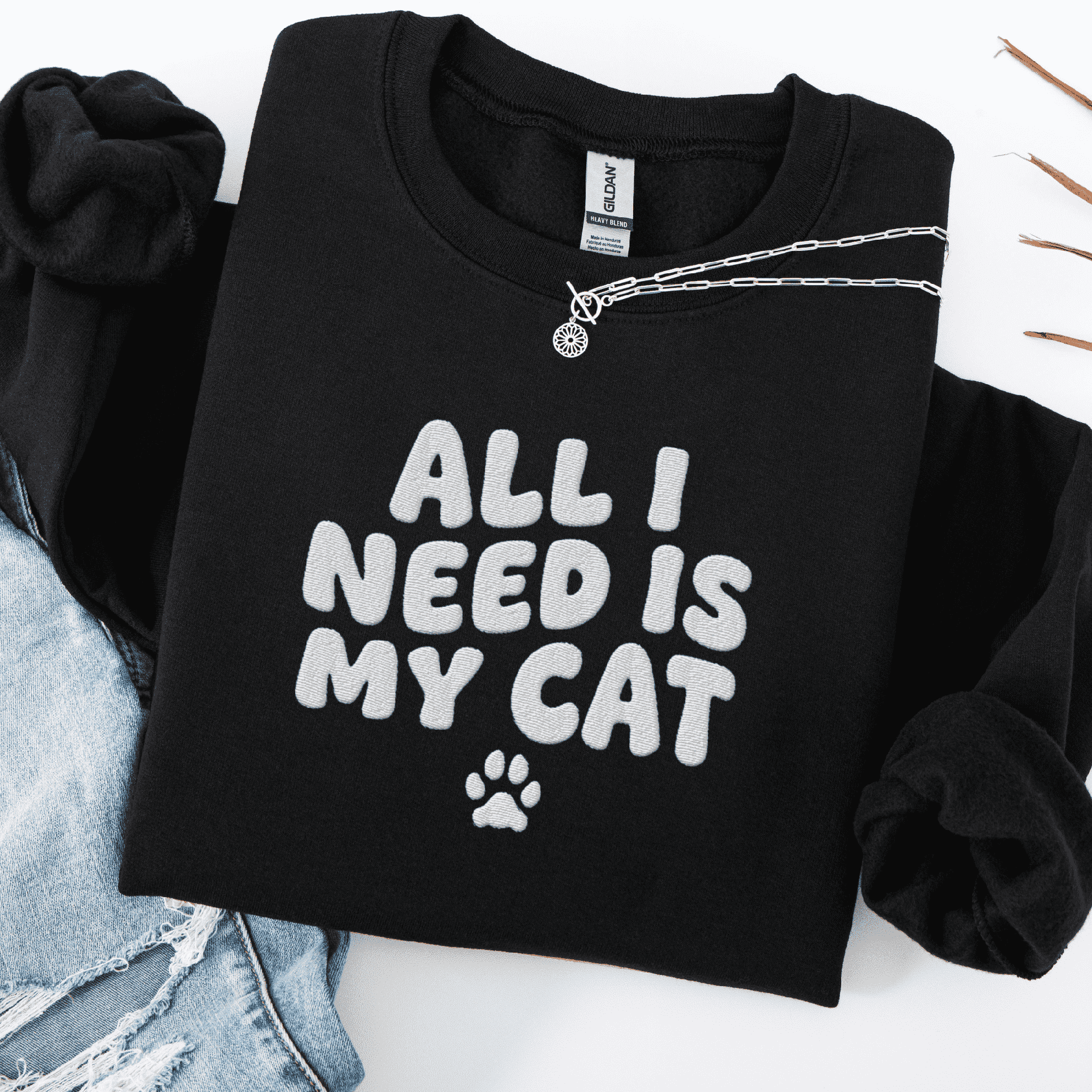 Black embroidered cat sweatshirt with the phrase “All I Need Is My Cat” shown folded flat