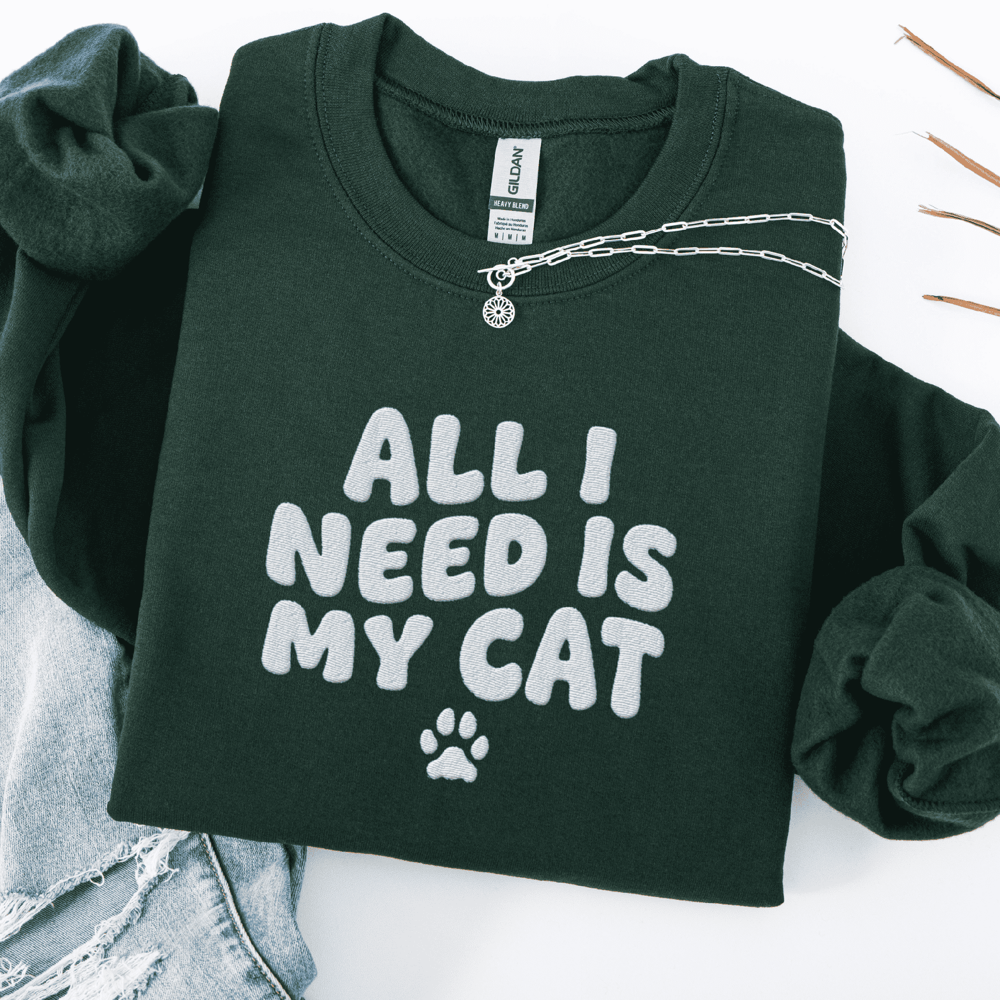 Forest Green embroidered cat sweatshirt with the phrase “All I Need Is My Cat” shown folded flat