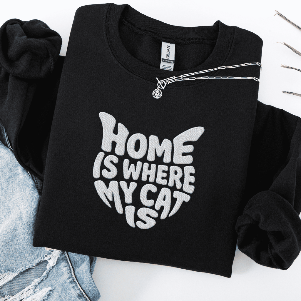 Black embroidered cat sweatshirt with the phrase “Home Is Where My Cat Is” shown folded flat
