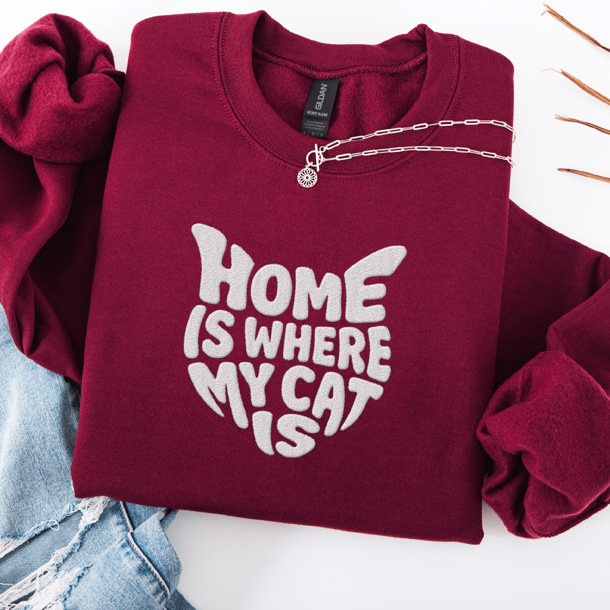 Maroon embroidered cat sweatshirt with the phrase “Home Is Where My Cat Is” shown folded flat